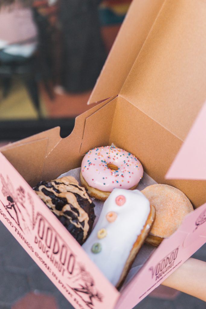 alt = "Pink Box filled with a variety of donuts".