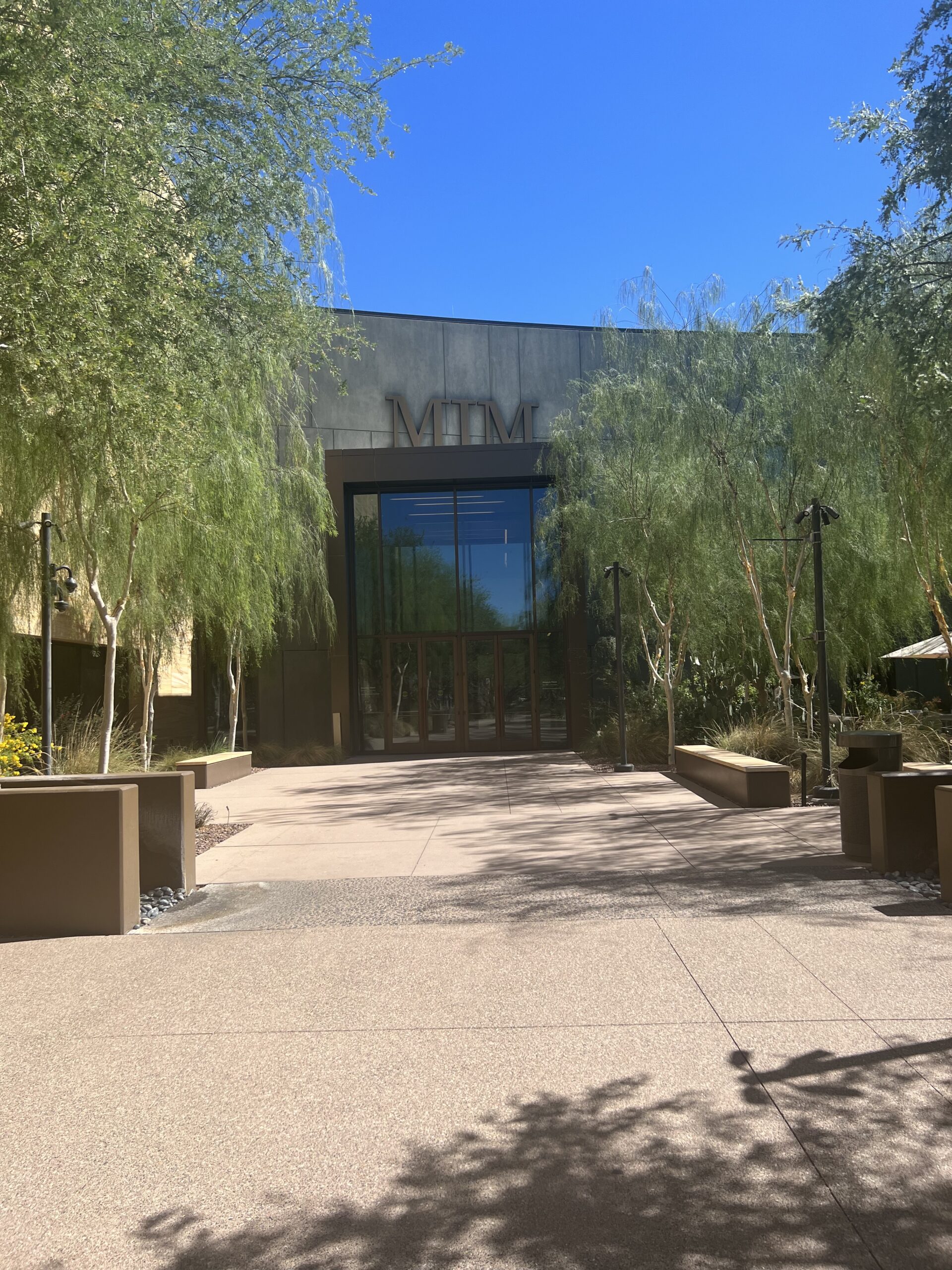 alt txt = "Musical Instrument Museum in Phoenix Entrance surrounded by greenery."