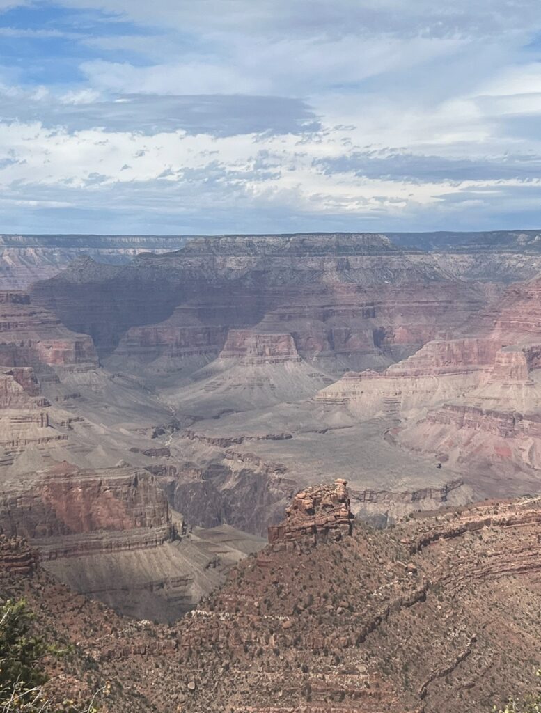 alt txt = "Gray, red, brown rocks and mountains surrounded by clear skies at the Grand Canyon."