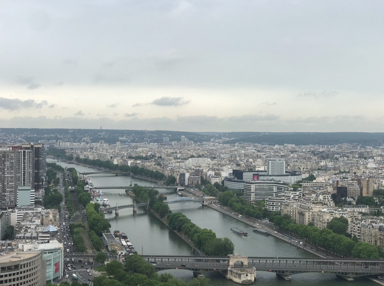 alt txt = "Views from the Eiffel Tower overlooking river and skyline."