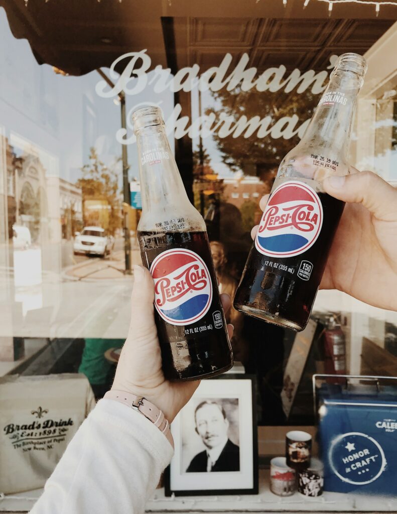 alt txt = "Two people holding Pepsi cola glasses in New Bern".