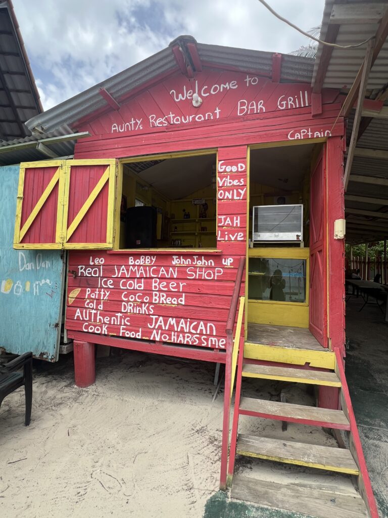 alt txt = "Restaurant with red signage selling Jamaican dishes".