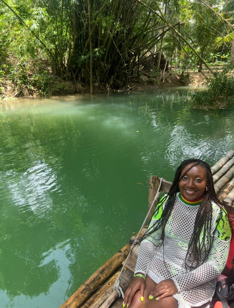 alt txt = "One African American woman on a bamboo raft floating down the Martha Brae river".