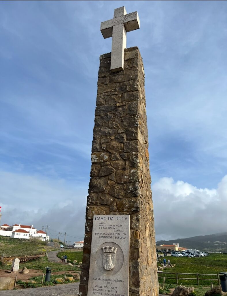 alt txt = "Stone monument with a cross at the top with writing written on the stone".