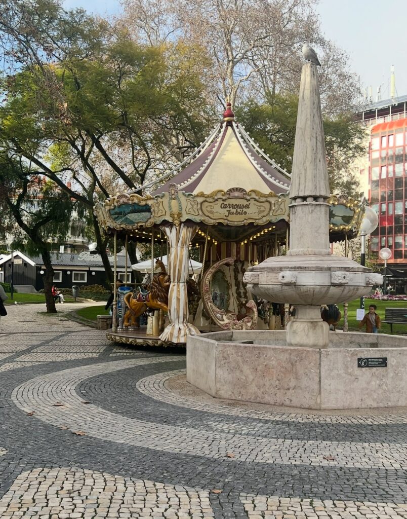 alt txt = "Carousel behind white monument in the town square".