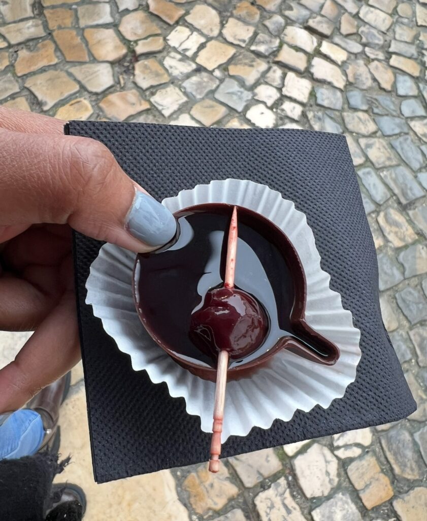 alt txt = "Black woman with blue nails holding cherry wine in a chocolate cup".