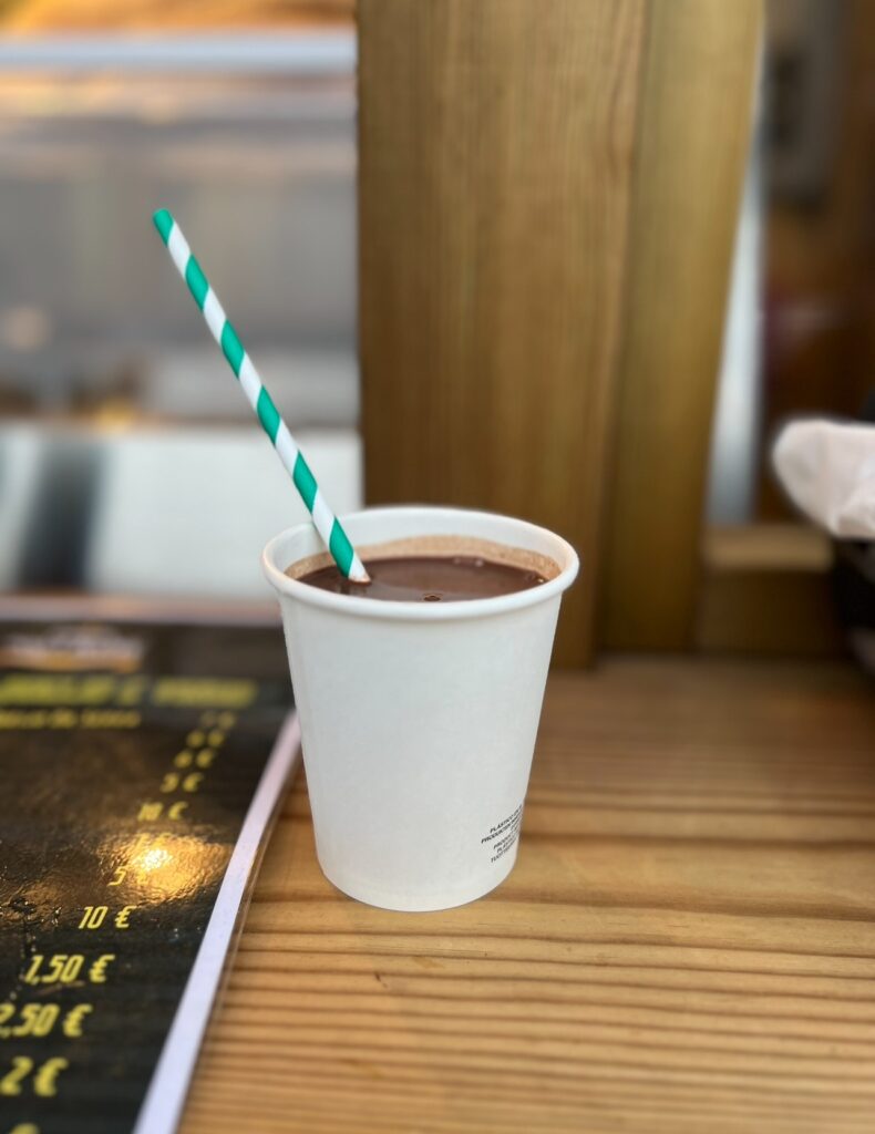 alt txt = "Chocolate drink in white cup with green and white paper straw".