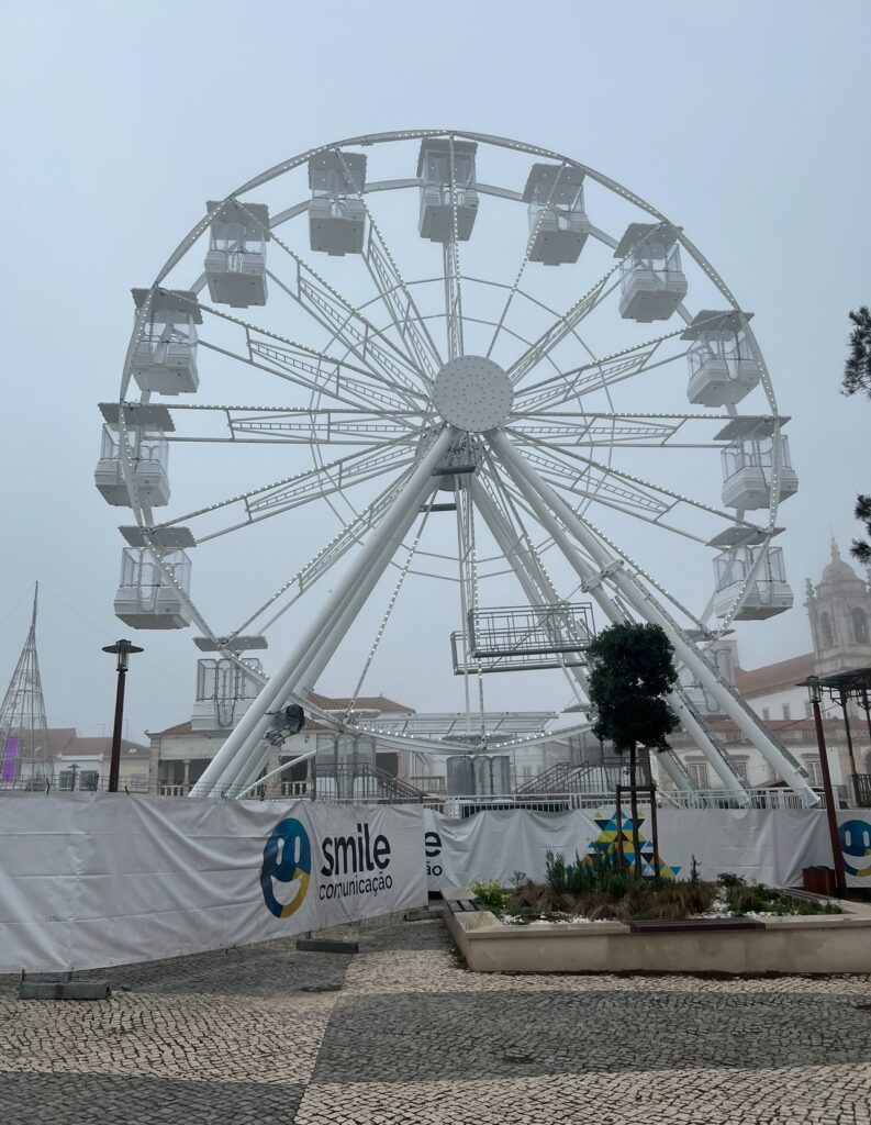 alt txt = "White Ferris wheel under grey skies".