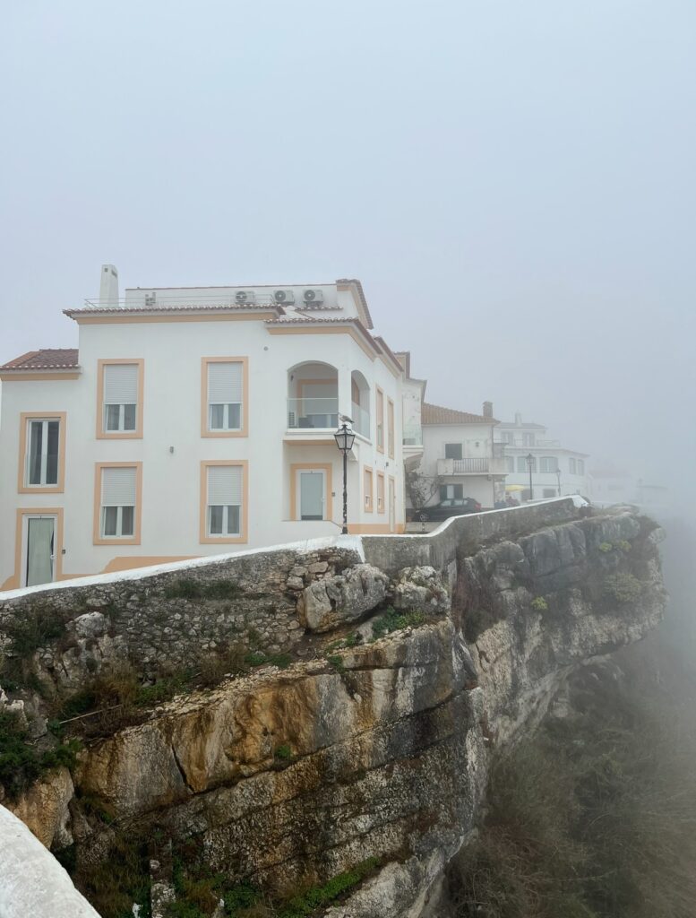 alt txt = "White and orange house on top of cliffs".