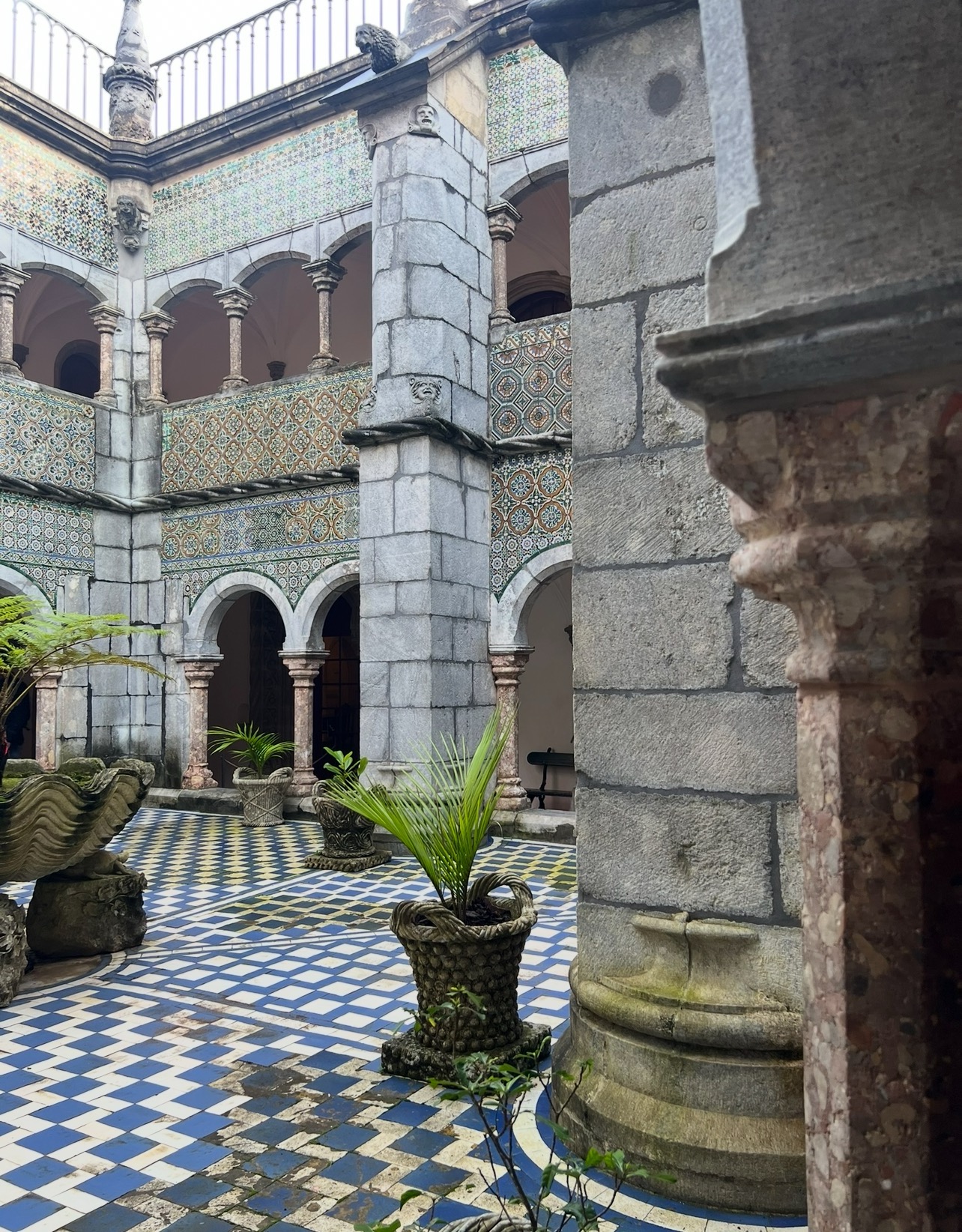 alt txt = "Blue and gray tile and sculptures surrounded by plants".