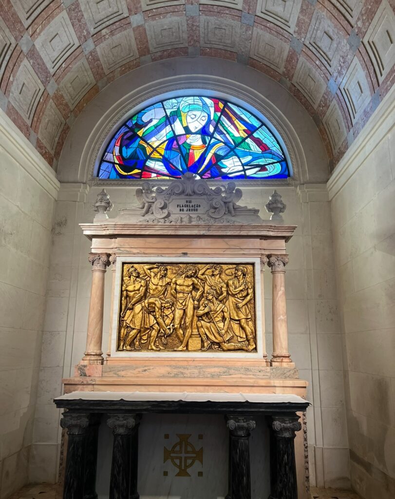 alt txt = "Stained church glass window atop shrine".