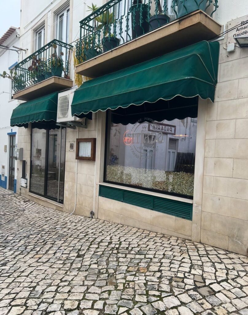 alt txt = "Green sign on top of cobblestone road".