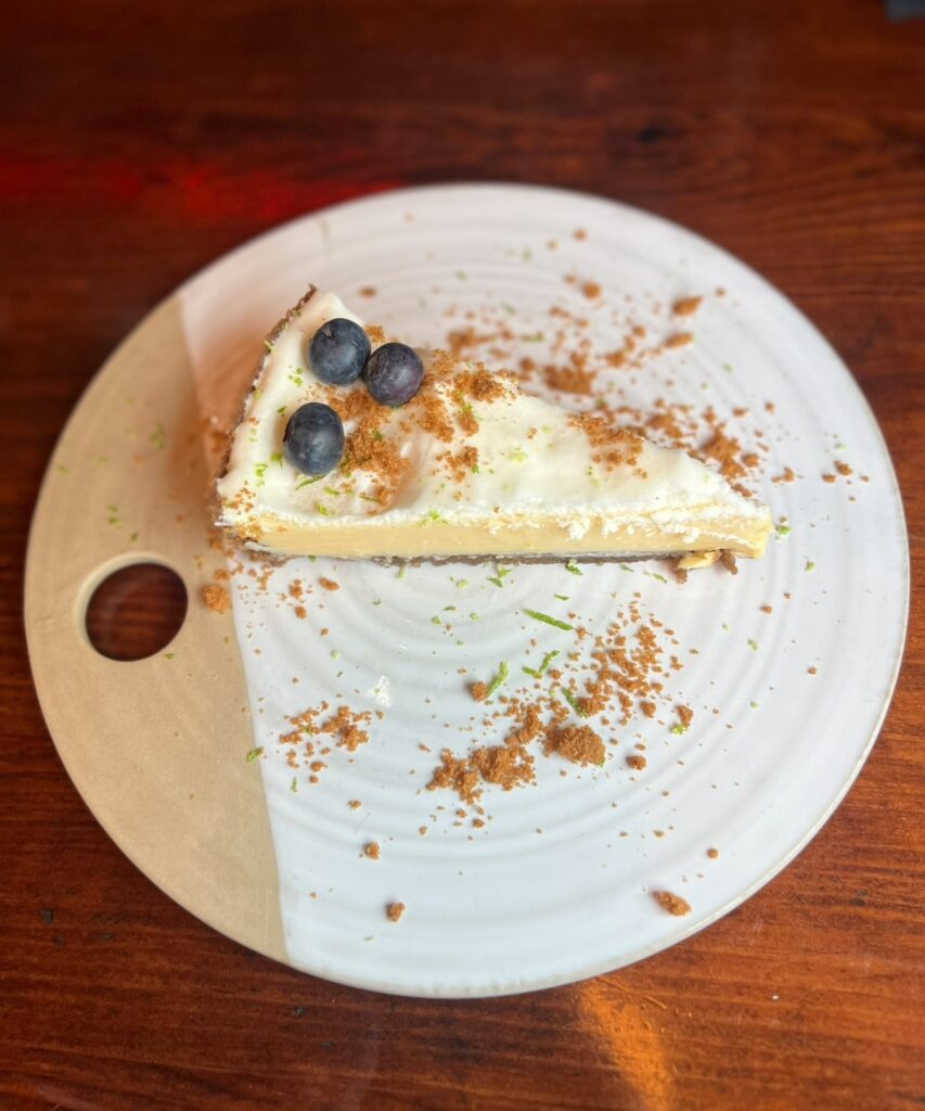 alt txt = "Lime tart surrounded by cookie crumbs on white plate".