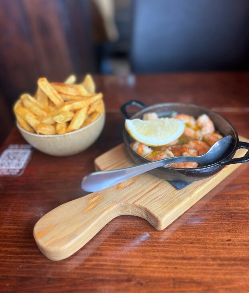 alt txt = "Shrimp inside black pot with French fries in white bowl".