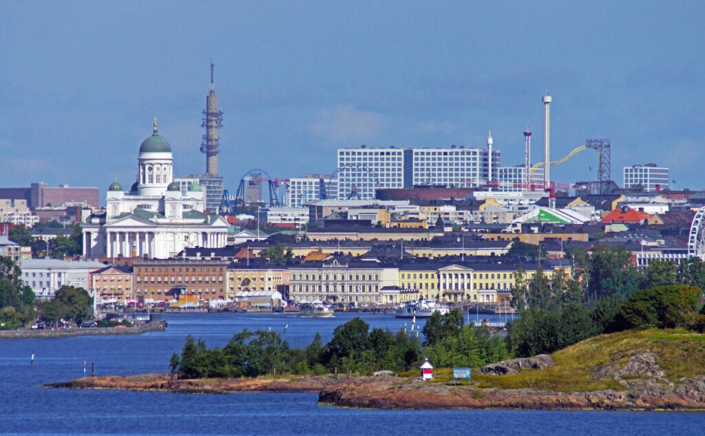 Helsinki, FinlandPanoramic view of Helsinki, Finland, showcasing the white Helsinki Cathedral, amusement park rides, and waterfront buildings under a blue sky.