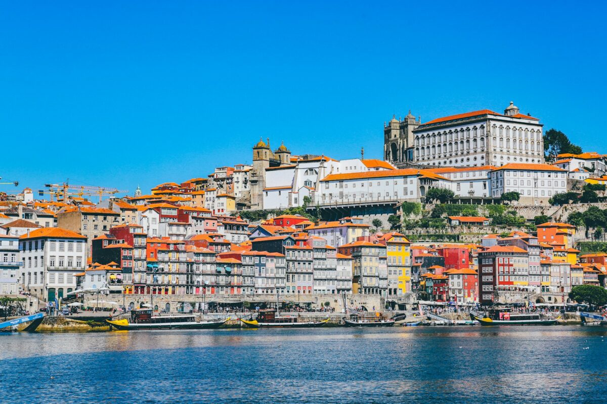 Porto, Portugal Colorful buildings with red-tiled roofs rise along the Douro River in Porto, Portugal, with boats docked by the lively Ribeira district.