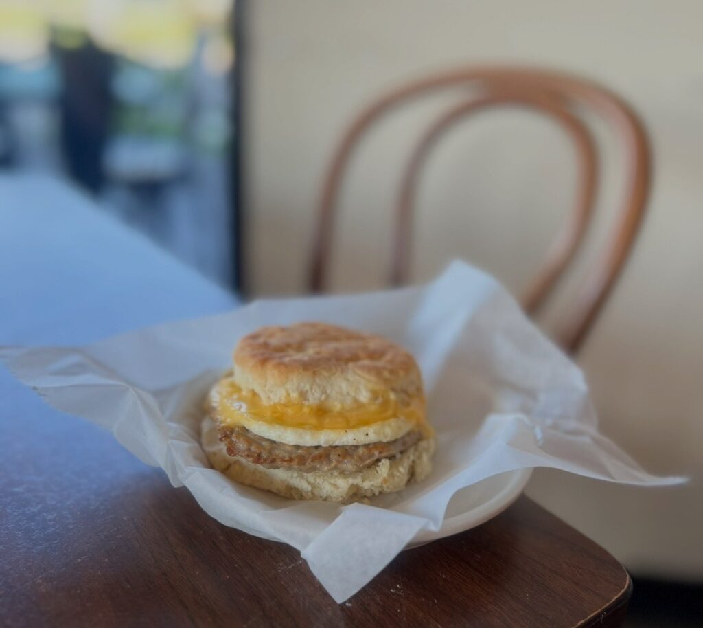 A breakfast sandwich with sausage, egg, and melted cheese wrapped in paper on a table. 